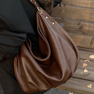 Brown leather hobo tote bag with vintage metal details for women shown on model