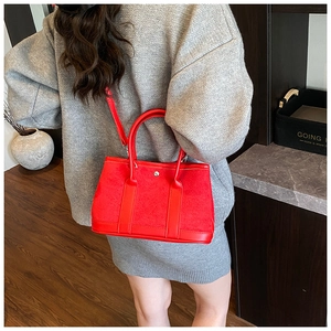 Detail of red suede bucket bag showing the metal buckle and crossbody strap on model
