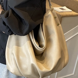 Minimalist beige pebble leather tote bag with gold metal studs and spacious interior