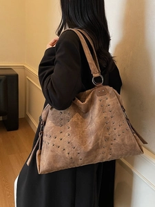 Grand sac cabas vintage marron avec rivets métalliques et anneaux porté à l'épaule