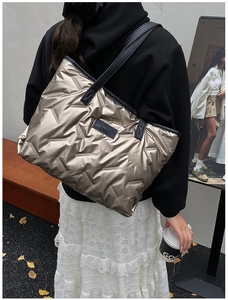 Detail der champagnerfarbenen Metallic-Stepptasche mit Hepulin-Logo und schwarzen Riemen