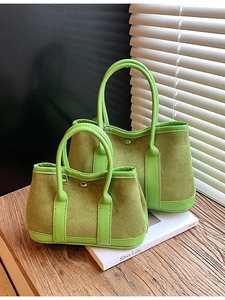 Avocado green suede tote bag set with leather handles on a minimalist wooden surface