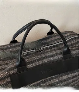 Détail du sac de voyage à motif chevrons avec poignée en cuir et logo Noco