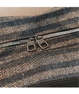 Détails des doubles fermetures éclair sur le tissu gris à chevrons du sac de sport