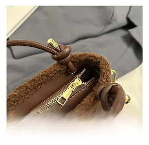 Gros plan du sac seau en cuir marron foncé avec bordure en peluche et détails dorés brillants