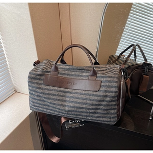 Détail du sac de voyage en toile à chevrons avec finitions en cuir marron chic