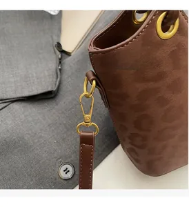 Dettaglio della borsa a secchiello marrone scuro leopardata con finiture in oro lucido