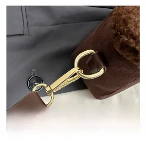 Gros plan sur les crochets dorés et les bandoulières en cuir marron d'un sac seau chic