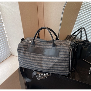 Sac de sport rayé avec poignées en cuir et compartiment à chaussures sur bureau noir