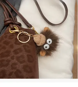 Dettaglio del portachiavi in peluche marrone con cappello su borsa leopardata