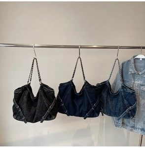 Three denim drawstring tote bags with chain straps in grey, dark blue and light blue denim
