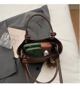 Dettaglio interno della borsa a secchiello in pelle marrone con spazio per telefono e portafoglio