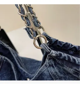 Detail view of denim tote bag showing silver metal chain strap and blue washed fabric