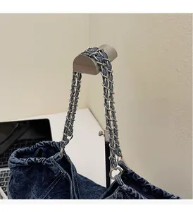 Detail of blue denim tote bag featuring vintage chain handle and stitching