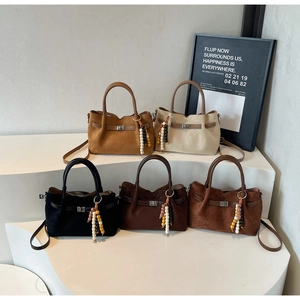 Détail de cinq sacs seaux en daim avec fermoirs pivotants rétro et pompons colorés