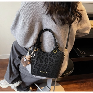 Dettaglio della borsa a secchiello nera leopardata con logo oro e ciondolo gufo
