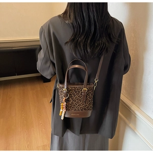 Détail du sac seau léopard avec bordure en cuir marron et pendentif à perles