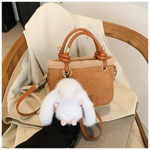 Dettaglio borsa a secchiello marrone scamosciata con bordo in shearling e charm a coniglio