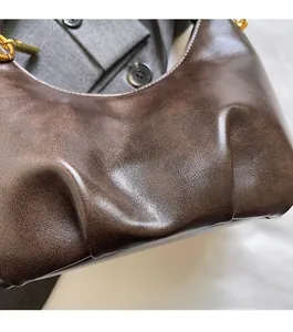 Close-up of brown vintage leather bag texture with golden embossed logo and metal chain