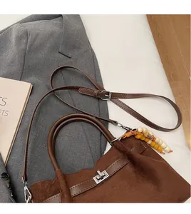 Détail du sac seau en daim marron avec bandoulière réglable et breloque en perles de bois