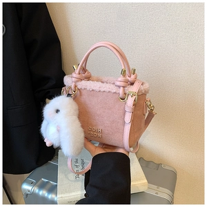 Dettaglio borsa a secchiello rosa in peluche e camoscio con hardware dorato e ciondolo coniglio
