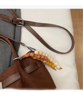 Détail du sac seau en daim marron avec pampilles décoratives en perles de bois rétro