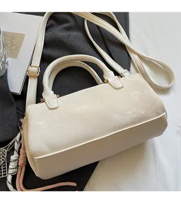 Close-up of cream white Boston bag featuring textured faux leather and braided charm detail