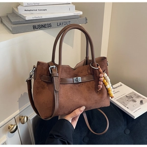 Détail du sac seau en daim avec pendentif en perles et fermoir rotatif argenté