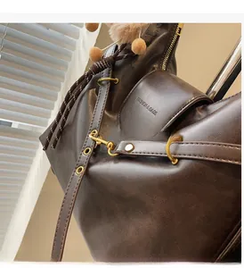Detail view of glossy oil-wax brown leather tote bag with gold hardware and embossed text