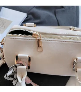 Close-up of smooth gold zipper and side woven strap detail on white Boston bag