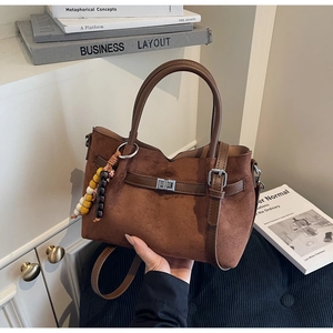 Détail du sac seau en daim marron foncé avec boucle en métal et breloque en perles colorées