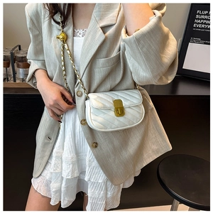 Detail of white quilted leather bag with vintage gold metal buckle and adjustable chain