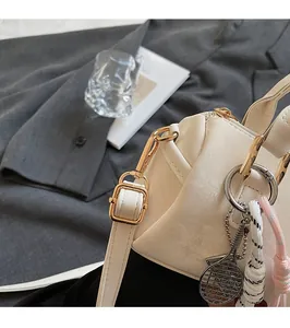 Detail of creamy white Boston bag with golden hardware and tennis racket charm