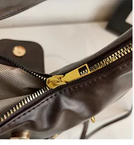Close-up of smooth gold zipper and herringbone fabric lining on dark brown tote bag