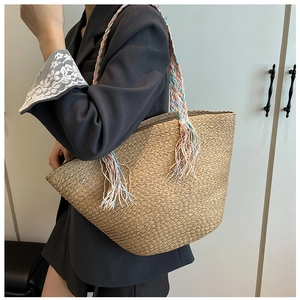 Detail of hand-woven straw tote bag with colorful braided rope handles and tassels