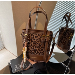 Détails d'un sac seau léopard avec breloques métalliques et reflet dans le miroir