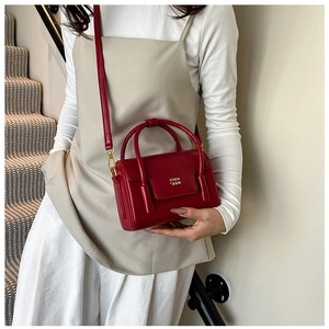Détail du sac boîte rouge montrant la finition brillante et les ferrures métalliques dorées