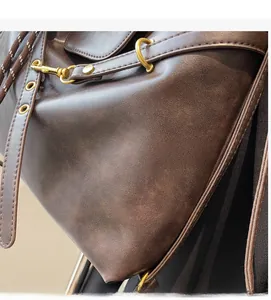 Detail of dark brown leather tote featuring gold metal D-rings and woven drawstring design