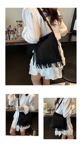 Detailed view of the black frosted faux leather shoulder bag with long flowing fringes