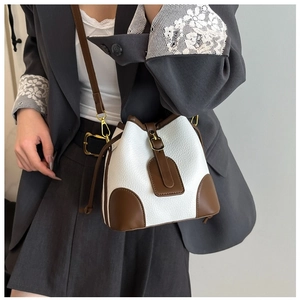 Detail of a contrasting color bucket bag in white and brown leather with adjustable strap