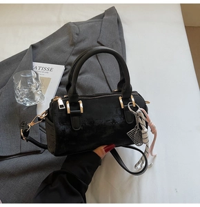 Detail view of black vintage Boston bag featuring retro velvet texture and woven tassel charm