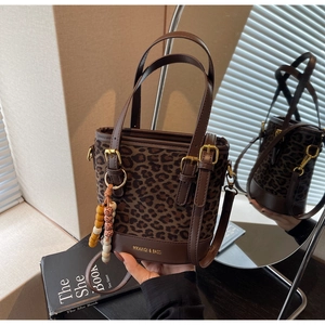 Gros plan détaillé du sac seau à motif léopard avec poignées en cuir brun et boucles d'or