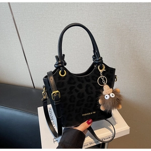 Dettaglio borsa a secchiello nera leopardata con logo dorato e ciondolo in peluche