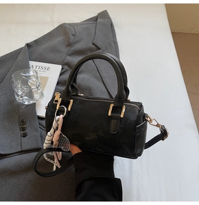 Retro black Boston bag with gold hardware and tennis racket charm on white bedding