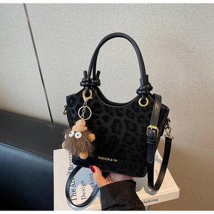 Dettaglio della borsa a secchiello leopardo nero con finiture dorate e ciondolo plush