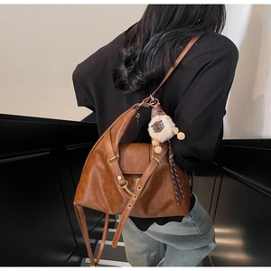 Detailed view of dark brown leather tote bag with sheep pendant and fashion logo