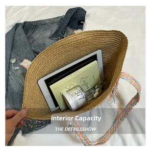 Top view of spacious straw tote interior holding a tablet, books, and colorful woven straps