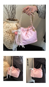 Detail of pink quilted bucket bag featuring a white lace bow and gold chain strap