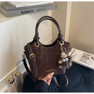 Dettaglio della borsa a secchiello leopardata caffè con ciondolo di peluche e logo di moda
