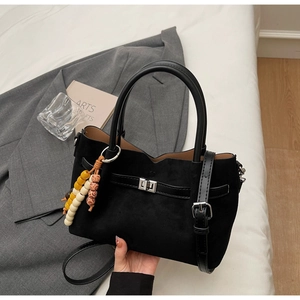 Détail du sac seau en daim noir avec fermoir rotatif argenté et breloque en perles
